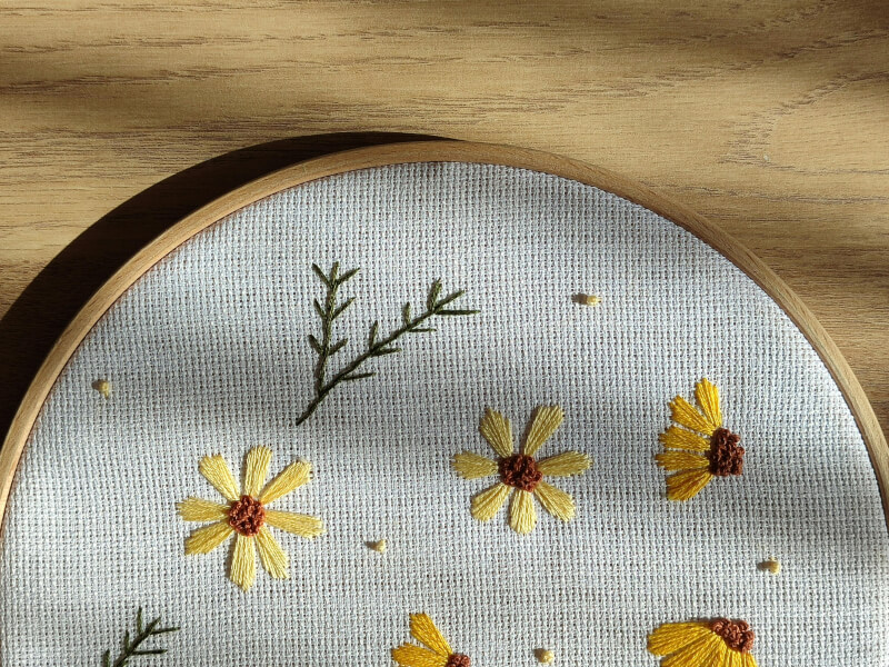 Close-up of embroidery hoop decorated with daisies